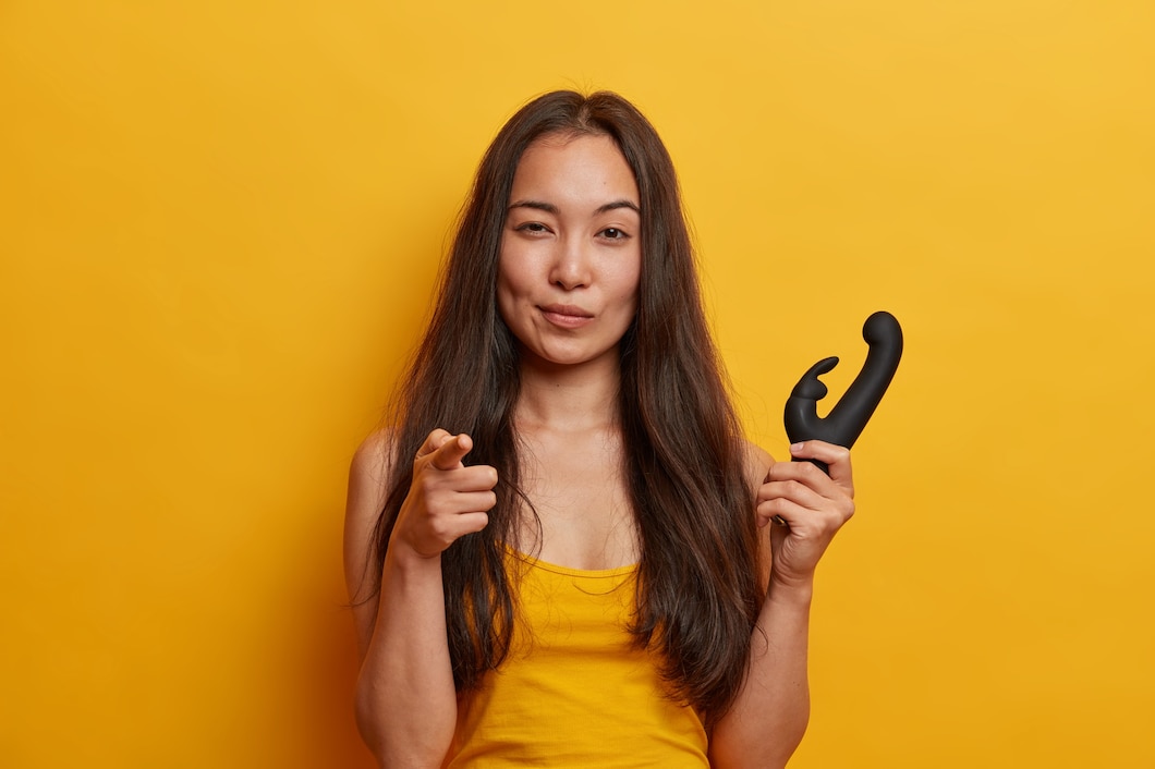 mujer joven segura si misma senala dedo indice sostiene vibrador estimular clitoris vibraciones centelleantes tiene consolador personal aislado pared amarilla juguete sexual mujeres 273609 39650
